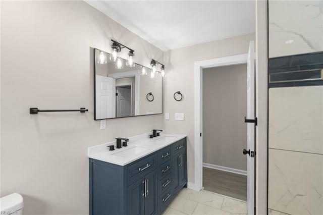 bathroom with marble finish floor, a sink, double vanity, and toilet