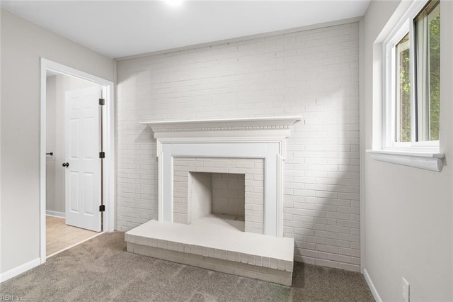 interior details featuring baseboards, a brick fireplace, and carpet