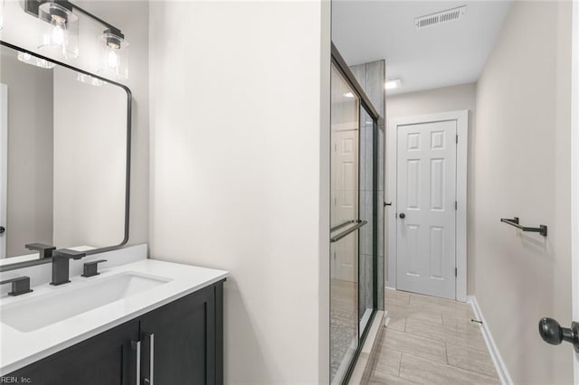 full bathroom with baseboards, visible vents, vanity, and a stall shower