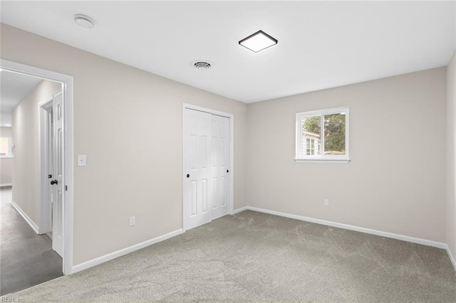 unfurnished bedroom featuring baseboards, carpet flooring, and visible vents