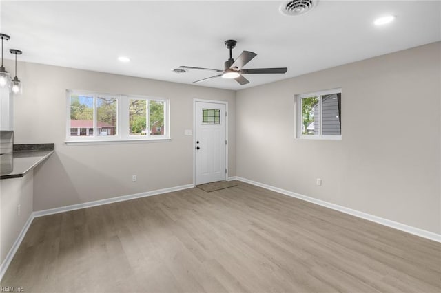interior space with baseboards, visible vents, light wood-style floors, and ceiling fan