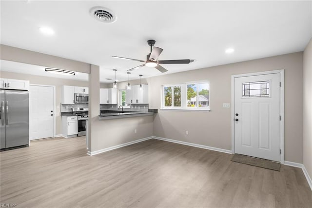 kitchen with dark countertops, a ceiling fan, light wood-style floors, stainless steel appliances, and visible vents