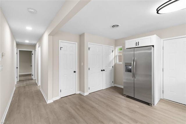 kitchen featuring light wood finished floors, white cabinets, baseboards, visible vents, and stainless steel refrigerator with ice dispenser