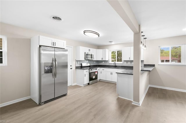 kitchen with dark countertops, visible vents, light wood-type flooring, baseboards, and appliances with stainless steel finishes