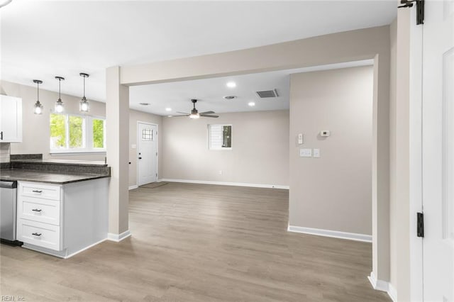kitchen featuring stainless steel dishwasher, a ceiling fan, dark countertops, baseboards, and visible vents