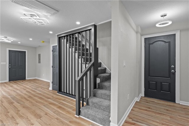 entryway with visible vents, baseboards, recessed lighting, wood finished floors, and stairs