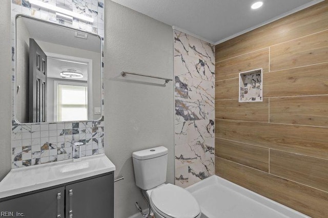 bathroom with decorative backsplash, toilet, vanity, and tiled shower