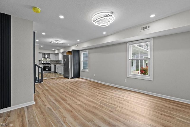 unfurnished living room with recessed lighting, light wood-style flooring, visible vents, and baseboards