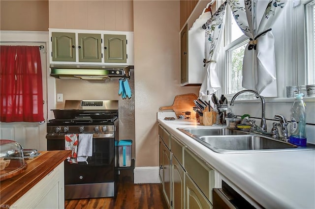 kitchen featuring dark wood-style floors, under cabinet range hood, a sink, gas stove, and baseboards