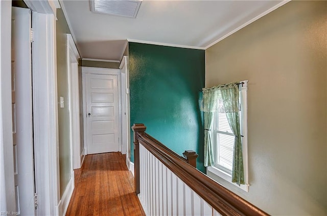 corridor featuring baseboards, visible vents, an upstairs landing, crown molding, and hardwood / wood-style flooring