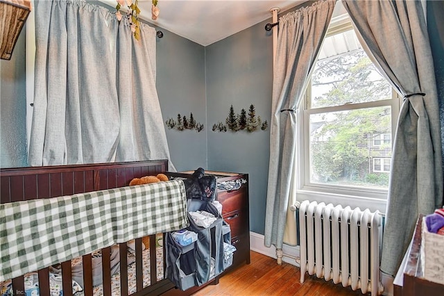 bedroom featuring radiator, baseboards, and wood finished floors