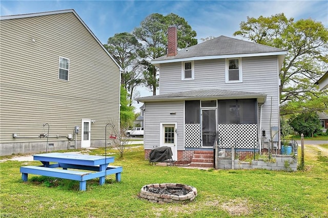 back of property featuring a fire pit, a chimney, a sunroom, and a yard