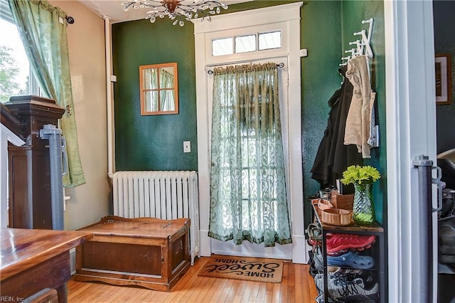 doorway to outside featuring hardwood / wood-style flooring, radiator, and a notable chandelier