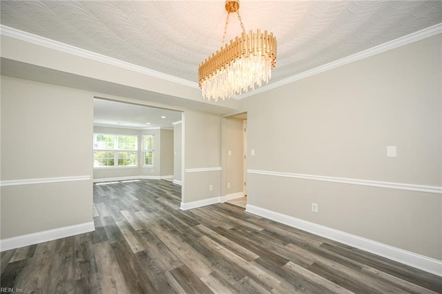 empty room with wood finished floors, crown molding, baseboards, and a notable chandelier