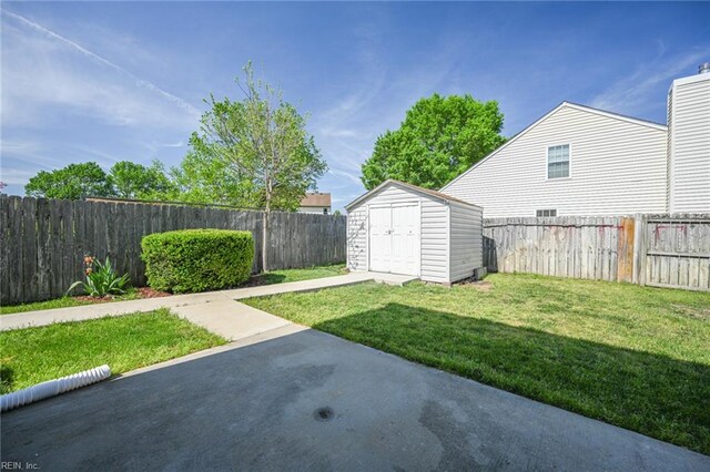 view of yard with a fenced backyard, an outdoor structure, a patio, and a shed