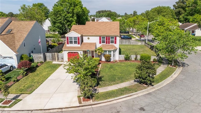 traditional home with fence, an attached garage, a front lawn, and concrete driveway