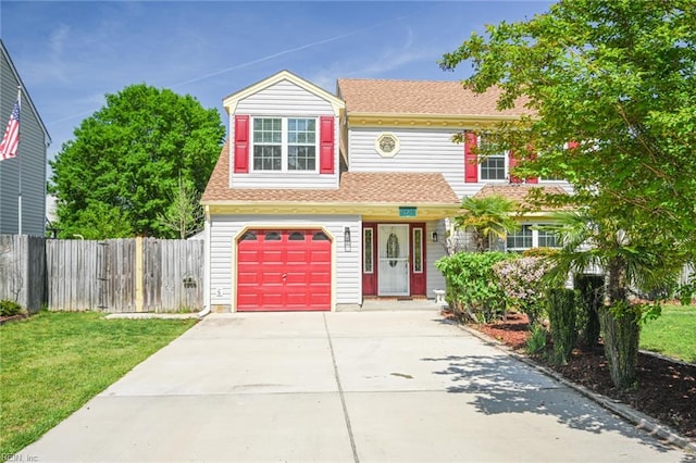 traditional-style house with concrete driveway, an attached garage, fence, and a front lawn