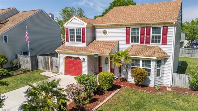 traditional-style house featuring fence, a shingled roof, concrete driveway, an attached garage, and a front yard