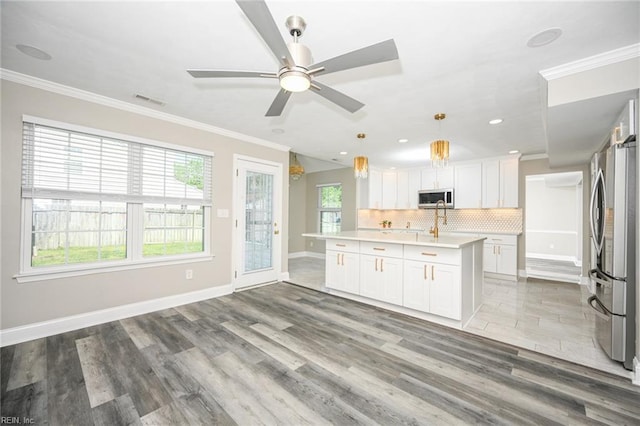 kitchen featuring light wood finished floors, light countertops, decorative backsplash, appliances with stainless steel finishes, and white cabinetry