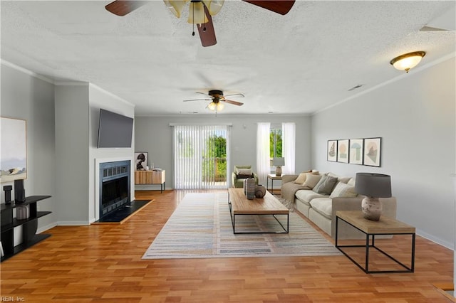 living area with a textured ceiling, a ceiling fan, and ornamental molding