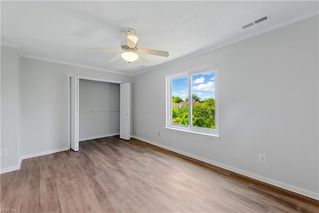 unfurnished bedroom with ornamental molding, wood finished floors, visible vents, and a closet