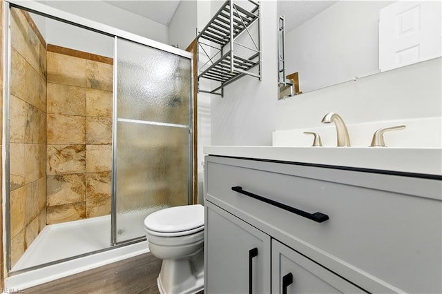 full bathroom featuring a shower stall, toilet, vanity, and wood finished floors