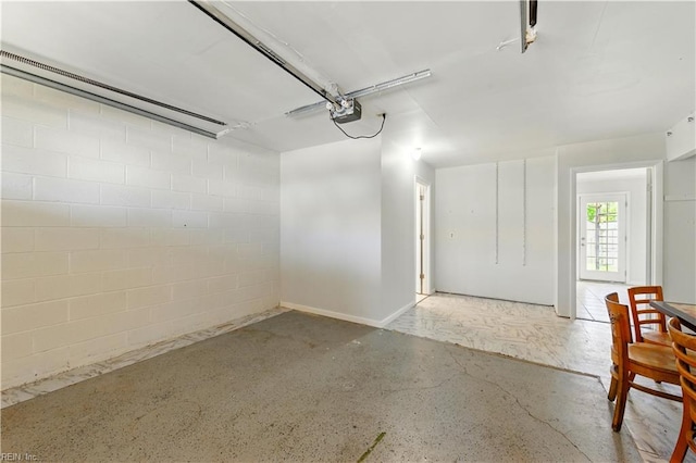 garage with a garage door opener and concrete block wall