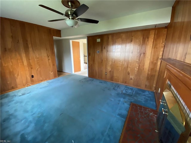 carpeted empty room with wood walls and a ceiling fan