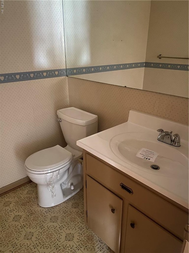 bathroom featuring wallpapered walls, vanity, and toilet