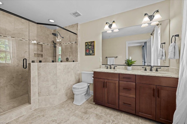 full bathroom with toilet, a sink, a shower stall, and visible vents