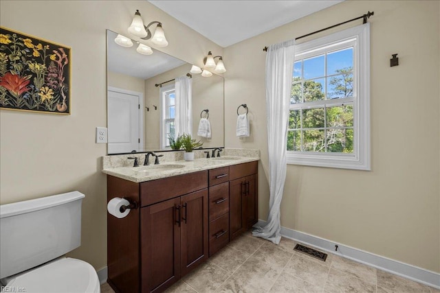 full bathroom featuring a sink, toilet, double vanity, visible vents, and baseboards