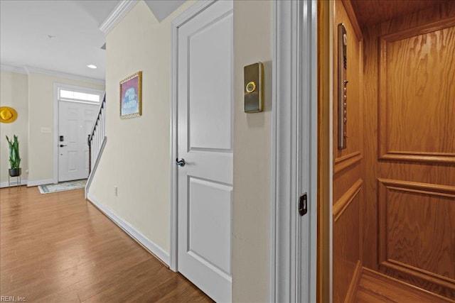corridor featuring recessed lighting, wood finished floors, baseboards, stairway, and crown molding