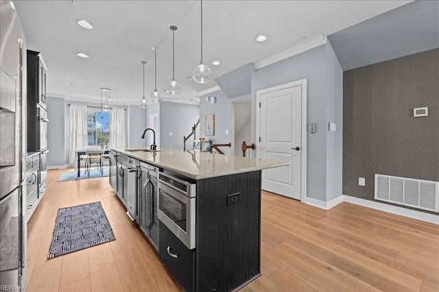 kitchen featuring a sink, dark cabinetry, crown molding, visible vents, and an island with sink