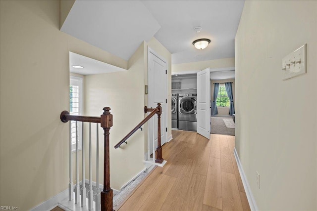 hall featuring light wood finished floors, an upstairs landing, independent washer and dryer, and baseboards
