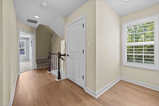 hall with visible vents, light wood-style flooring, and baseboards
