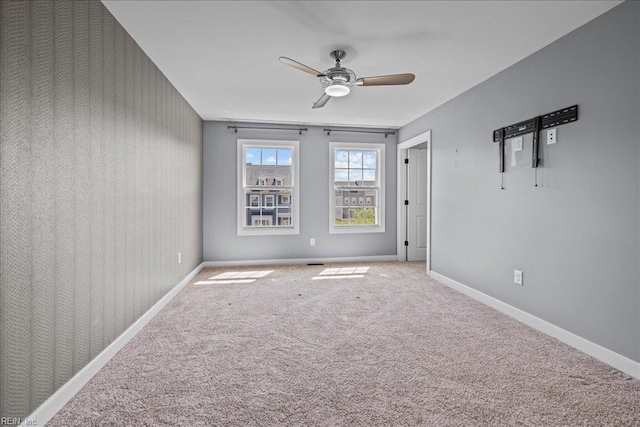 spare room with baseboards, ceiling fan, and carpet