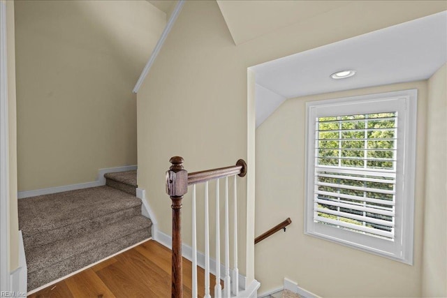 stairway with wood finished floors, vaulted ceiling, and baseboards