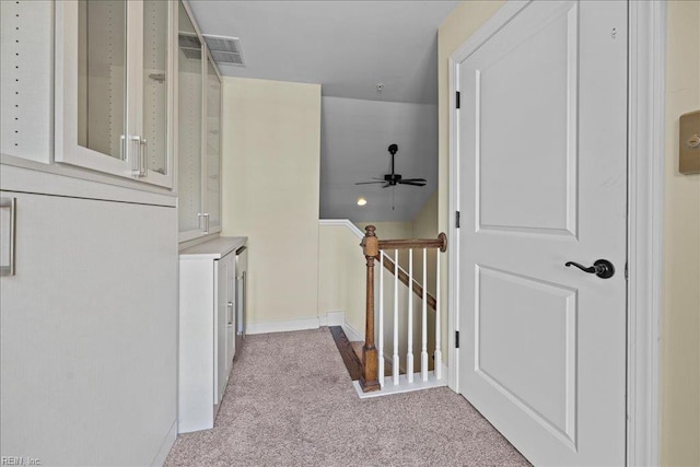 hallway featuring visible vents, light carpet, and an upstairs landing