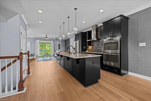 kitchen featuring stainless steel appliances, crown molding, wall chimney exhaust hood, wallpapered walls, and dark cabinets