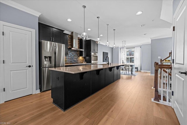 kitchen with dark cabinets, stainless steel fridge with ice dispenser, crown molding, and wall chimney exhaust hood