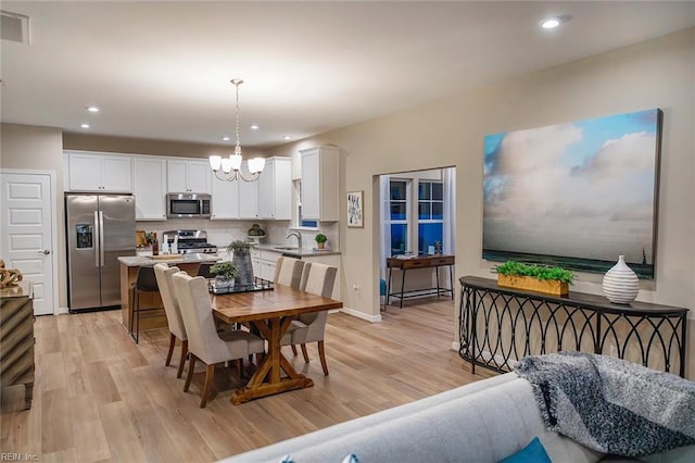 dining area with recessed lighting, an inviting chandelier, visible vents, and light wood-type flooring