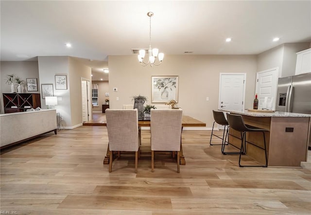 dining space with recessed lighting, baseboards, an inviting chandelier, and light wood-type flooring