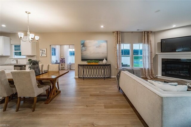 dining space featuring recessed lighting, plenty of natural light, light wood finished floors, and a notable chandelier