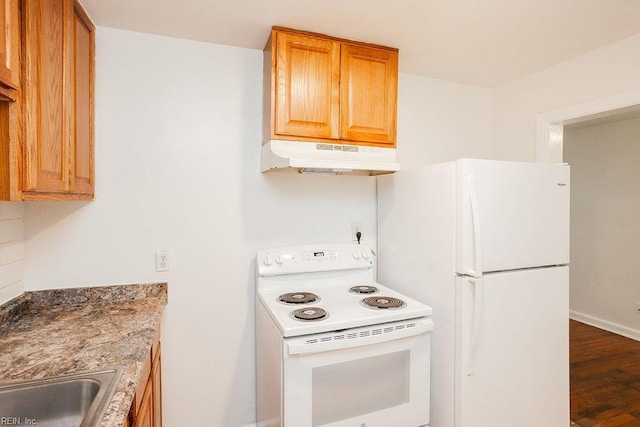 kitchen featuring a sink, white appliances, baseboards, under cabinet range hood, and dark wood-type flooring