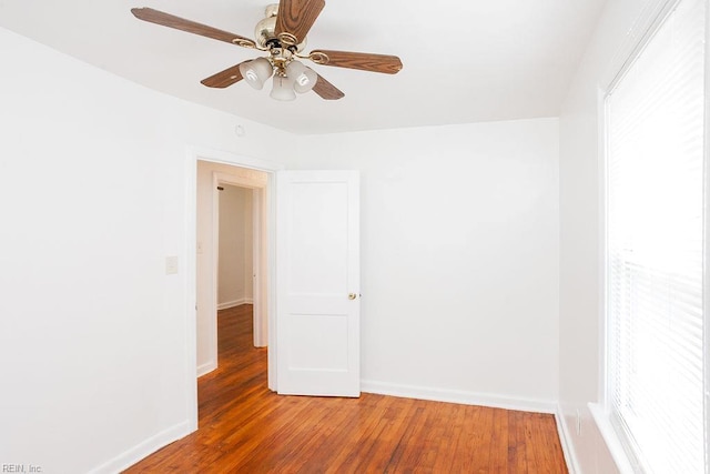 empty room featuring wood finished floors, a ceiling fan, and baseboards