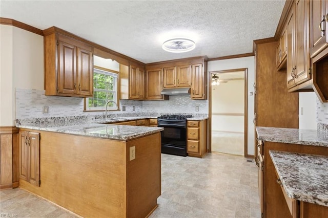 kitchen featuring a peninsula, a sink, black range with electric stovetop, brown cabinetry, and under cabinet range hood