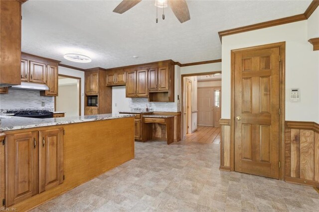 kitchen with decorative backsplash, a ceiling fan, light stone counters, crown molding, and under cabinet range hood