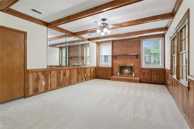 unfurnished living room with light carpet, beam ceiling, visible vents, ceiling fan, and a fireplace