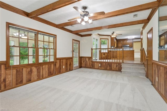 spare room featuring wainscoting, ceiling fan, light carpet, and beamed ceiling