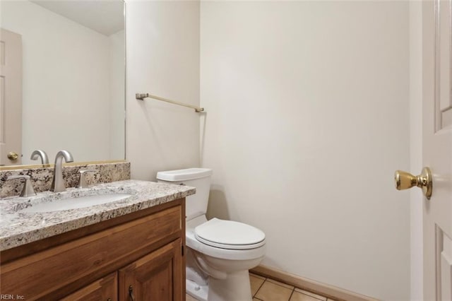 bathroom featuring baseboards, vanity, tile patterned flooring, and toilet